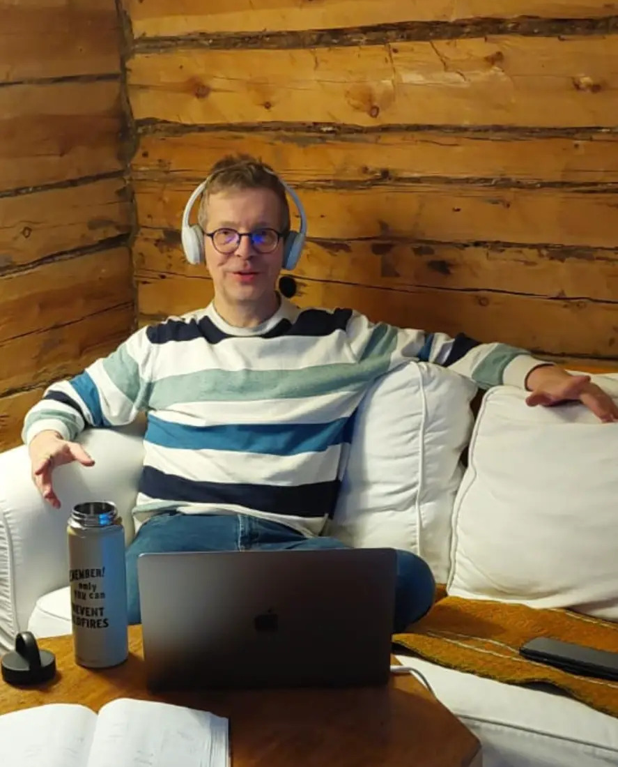 Aaron teaching a Teams lesson from a log cabin, wearing a headset